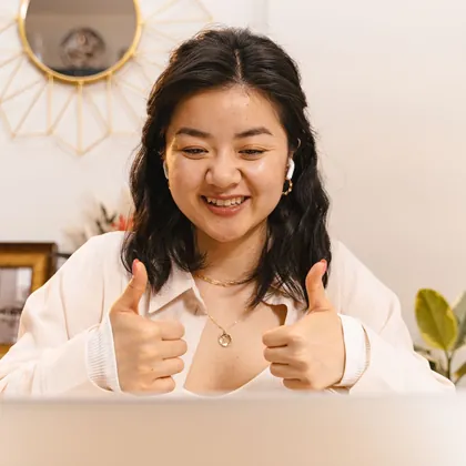 Cô gái giơ hai ngón cái trước màn hình laptop