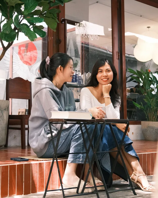 Hai bạn gái trò chuyện ở quán cà phê ngoài trời