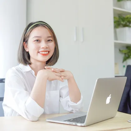 Cô gái mỉm cười ngồi bên laptop